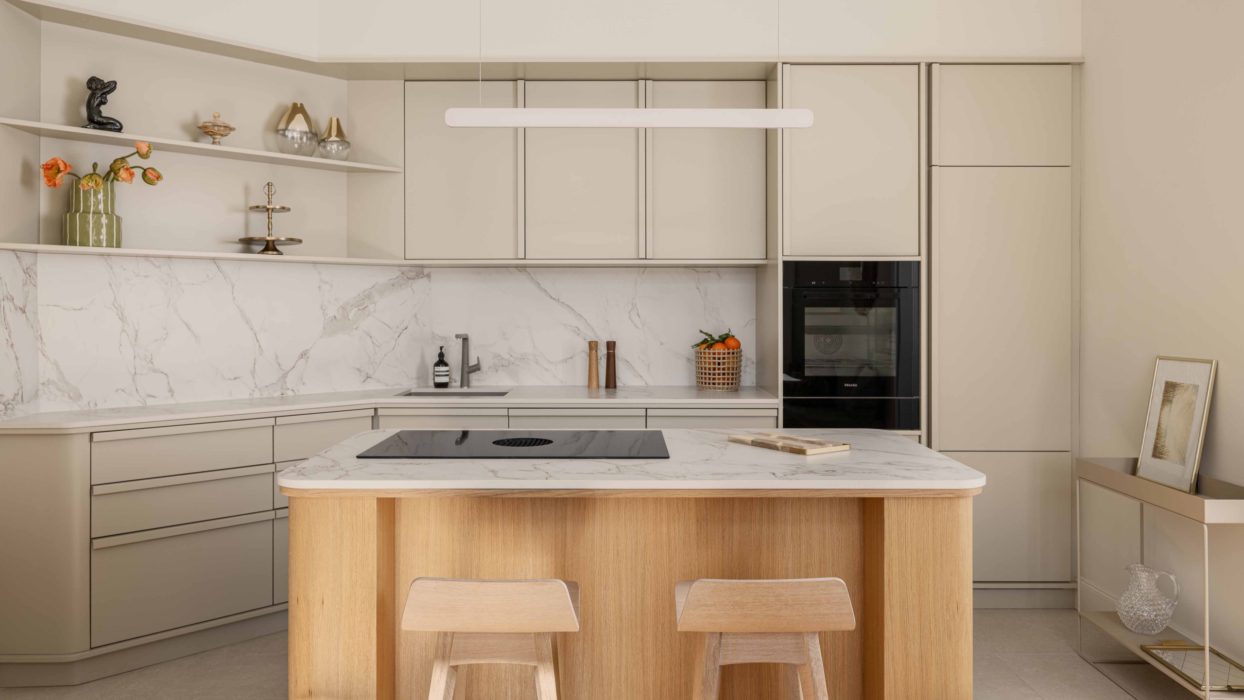 Moderne Designküche mit heller Front, Kücheninsel aus hellem Holz und edler Marmoroptik. Altbauflair. Offene Regale, integrierte Geräte und stilvolle Dekoration schaffen eine elegante und funktionale Atmosphäre – perfekt für hochwertige Wohnküchen im Contemporary Style.